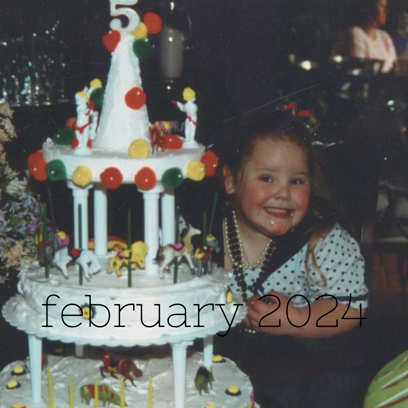 a square image of a five year old in polka dots behind a three-tiered circus themed birthday cake with the text february 2024 toward the bottom center