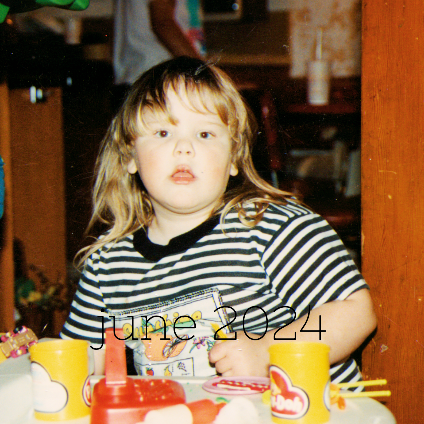 a square image of a kid anywhere from age four to seven tbh with bangs and a black and white striped shirt mouth hanging open while sitting at a table full of play doh accoutrements