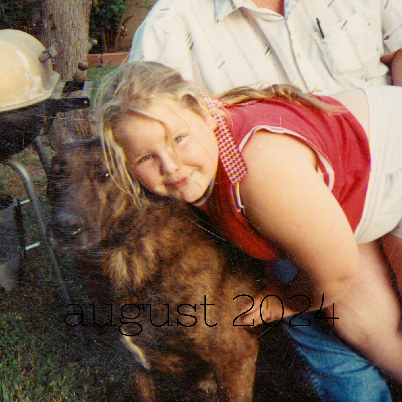 a square image of a kid anywhere from six to ten tbh with blonde hair tied back and a red shirt leaning over to hug a large brindle dog named kitty