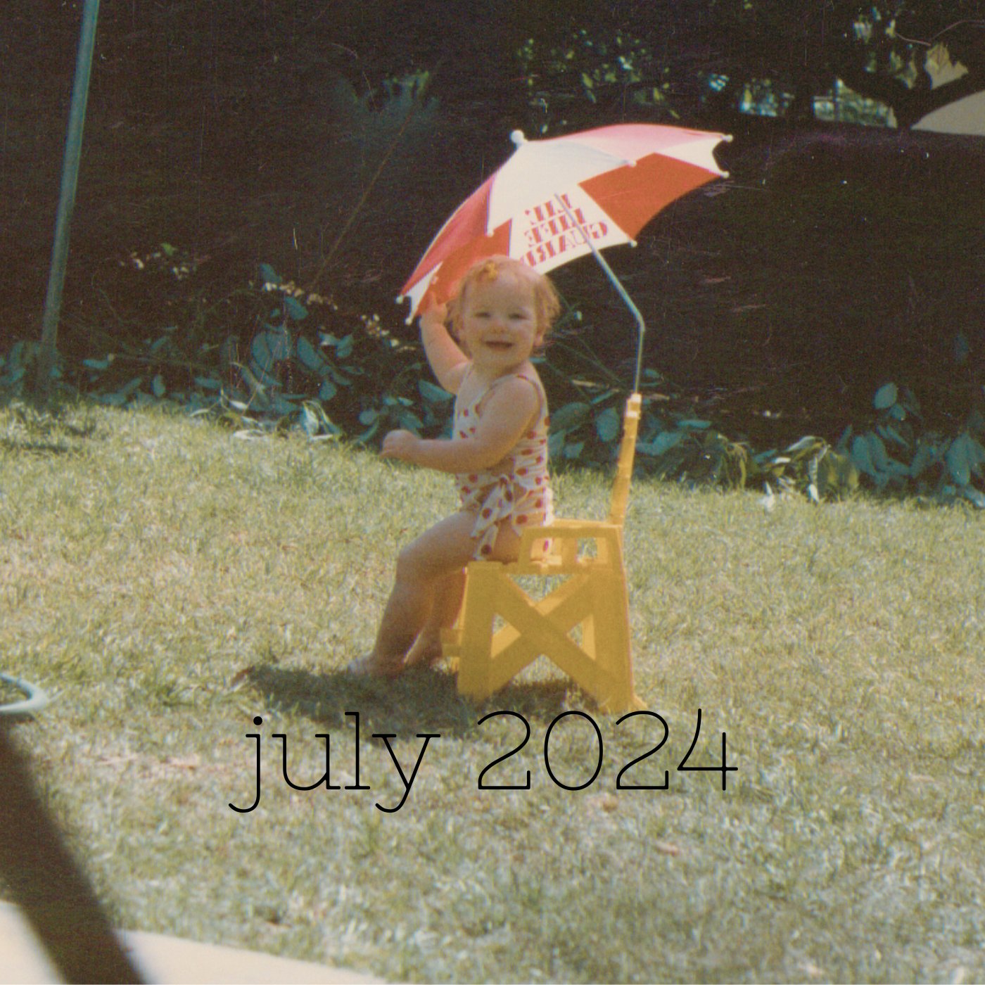 a square image of a kid anywhere from age two to four tbh with short reddish hair wearing a red and white polka dot bathing suit and sitting in a yellow toy lifeguard chair under a red and white umbrella
